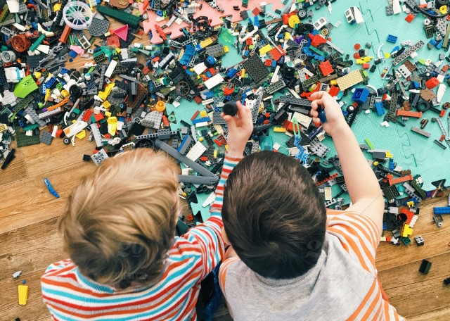 boys laying on the floor surrounded by toy building bricks